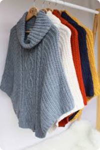 Batwing jumpers on a clothing rail in pale grey, cream, rust red, navy blue and mustard yellow